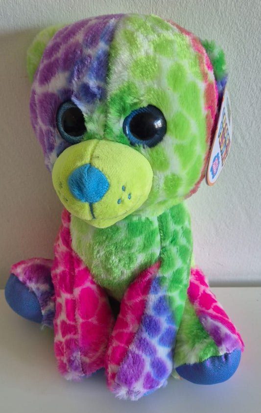 Pluche beer in felle regenboogkleuren met groene, paarse en roze vacht met giraffeprint, blauwe glinsterende ogen en blauwe neus.